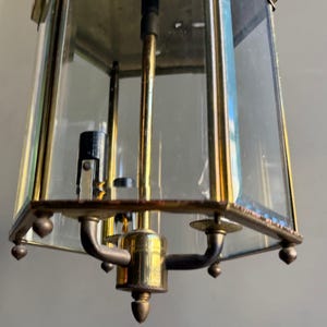 Puede incluir: Una lámpara colgante octogonal de latón y vidrio con tres brazos y una pantalla de vidrio transparente. La lámpara tiene un acabado dorado y está en buen estado.