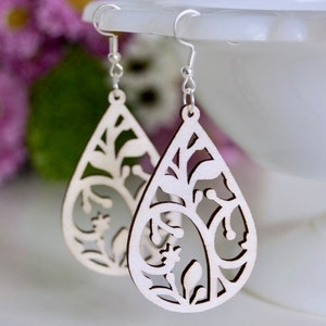 May include: A pair of wooden earrings with a delicate floral design. The earrings are shaped like teardrops and have a natural wood finish.