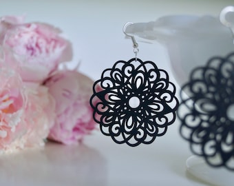 May include: A pair of black dangle earrings with a delicate, intricate floral design. The earrings are made of a lightweight material and have a silver hook closure.