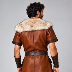 Men’s Viking leather tunic costume in brown leather with a wide fur shoulder collar, dark brown trim, adjustable buckle closures, waist belt, utility pouches, and matching leather forearm bracers. Front and back views show the knee-length Norse warrior tunic with short sleeves, fur across the shoulders, fitted belt, and medieval detailing. Ideal for Viking cosplay, LARP, Renaissance fairs, Halloween, fantasy events, and Norse warrior costumes.