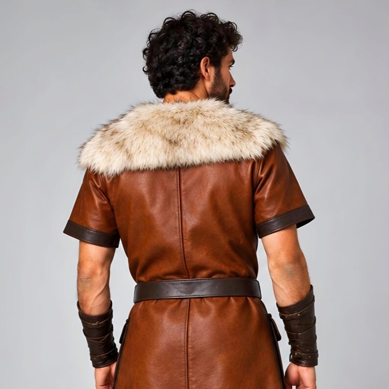 Men’s Viking leather tunic costume in brown leather with a wide fur shoulder collar, dark brown trim, adjustable buckle closures, waist belt, utility pouches, and matching leather forearm bracers. Front and back views show the knee-length Norse warrior tunic with short sleeves, fur across the shoulders, fitted belt, and medieval detailing. Ideal for Viking cosplay, LARP, Renaissance fairs, Halloween, fantasy events, and Norse warrior costumes.