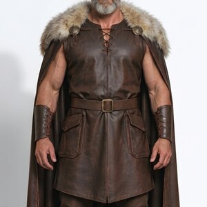 Men’s brown Viking leather tunic with a full-length matching cloak, large light fur shoulder collar, lace-up neckline, wide leather belt, front utility pockets, and matching leather forearm bracers. Front and back views show the sleeveless Norse warrior tunic and long flowing fur-trimmed cloak. Ideal for Viking cosplay, medieval LARP, Renaissance fairs, Halloween, fantasy conventions, stage costumes, and Norse warrior events.