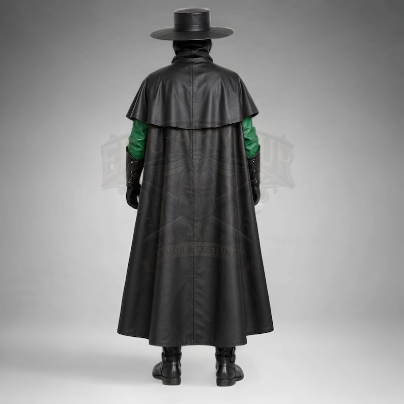Man wearing a green leather plague doctor costume with a long lace-up coat, black buckle belt and flowing black cloak. A shoulder capelet frames the upper body, while quilted black bracers cover the forearms. The outfit is styled with black gloves, leg guards, boots, a wide-brimmed hat and a beaked mask with round eyepieces. He holds edge of the cloak and stands against a plain gray background. The vivid green coat contrasts with the black accessories, showing the costume's gothic fantasy style.