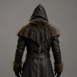 Black leather plague doctor coat with a dramatic fur-trimmed hood, shoulders, cuffs, front edges, and hem. Long medieval-inspired silhouette with lace-up front, wide adjustable leather belt, fitted sleeves, and dark gothic styling. Ideal for plague doctor cosplay, Halloween costume, LARP, Renaissance fairs, medieval festivals, fantasy events, gothic photoshoots, theatrical performances, and themed parties. Handmade leather costume coat with custom sizing available for a personalized fit.
