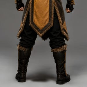 Black leather Viking ninja armor costume with antique gold leather panels, fur-trimmed shoulders, deep hood, adjustable waist belt, layered front armor, matching leather arm bracers, wrist guards and lower leg armor. Handmade medieval fantasy outfit with a rugged warrior-inspired design, suitable for Halloween, LARP, cosplay, Renaissance fairs, conventions, themed parties and fantasy photoshoots. Custom sizing and color options available.