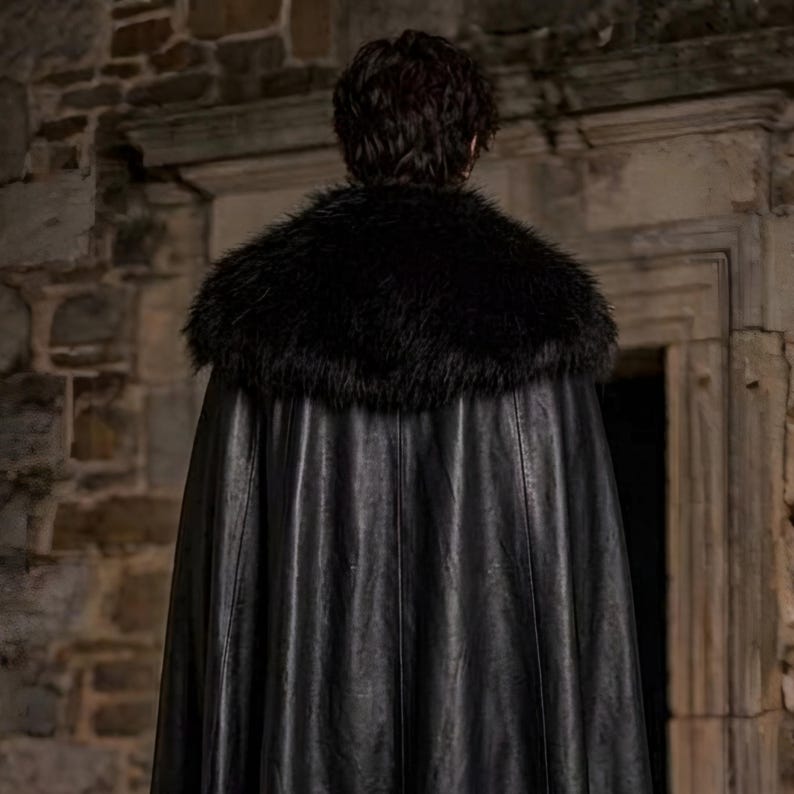 Men’s red and black Gothic vampire leather coat featuring a high standing collar, black fur-trimmed shoulders, double-breasted button detailing, wide waist belt, cross-body leather strap, long sleeves, and a dramatic floor-length silhouette. The dark Victorian-inspired design creates a Vampire Lord look ideal for Halloween, gothic cosplay, LARP, Renaissance fairs, masquerade events, fantasy conventions, stage performances, costume parties, and themed photoshoots.