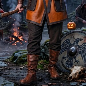 Men’s Viking leather tunic costume in brown leather with a wide fur shoulder collar, dark brown trim, adjustable buckle closures, waist belt, utility pouches, and matching leather forearm bracers. Front and back views show the knee-length Norse warrior tunic with short sleeves, fur across the shoulders, fitted belt, and medieval detailing. Ideal for Viking cosplay, LARP, Renaissance fairs, Halloween, fantasy events, and Norse warrior costumes.