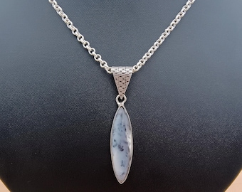 May include: A silver necklace with a long, teardrop-shaped pendant. The pendant features a white and gray stone. The necklace is displayed on a black jewelry stand.