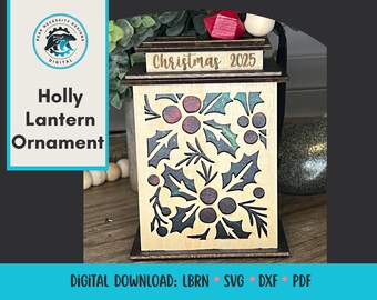 May include: Wooden Holly Lantern Ornament with laser-cut design. The ornament features a rectangular shape with a holly and berry pattern. The top of the lantern has the text "Christmas 2025". The design includes the text "Holly Lantern Ornament" and "Digital Download: LBRN SVG DXF PDF".