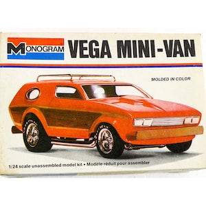 Könnte beinhalten: Ein Monogram Vega Mini-Van 1/24 Modellbausatz-Karton. Die Verpackung zeigt eine Illustration eines orangefarbenen Vans mit holzmaserter Seitenverkleidung, einem Dachträger und Chromfelgen. Der Text lautet Monogram Vega Mini-Van und Molded in Color.