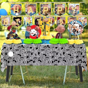 May include: A birthday party table setting with a banner that says "HAPPY BIRTHDAY". The table is covered with a black and white patterned tablecloth and decorated with character figurines and honeycomb centerpieces. Balloons are in the background.