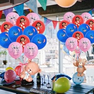 Puede incluir: Una escena festiva con globos coloridos con personajes de dibujos animados. Globos rosas, rojos y azules est&aacute;n agrupados, con un oso de peluche y otras decoraciones de fiesta sobre una mesa. Los globos tienen im&aacute;genes de Stitch y Lilo.