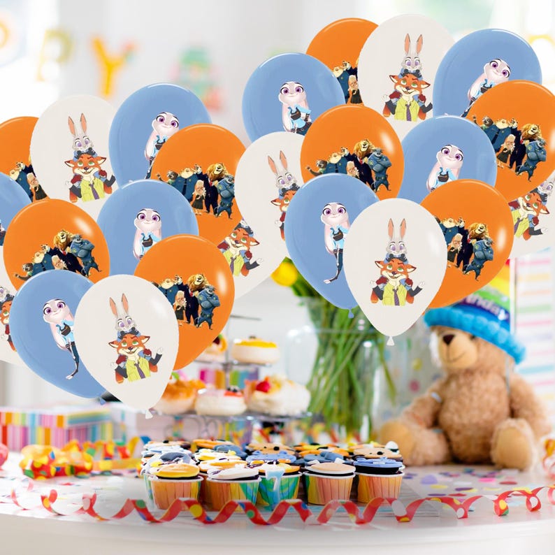 May include: A selection of orange, blue, and white balloons, each printed with cartoon characters. The balloons are arranged to create a celebratory atmosphere. Cupcakes and a teddy bear are also visible, suggesting a party or event.