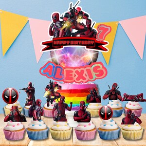 May include: A Deadpool-themed birthday cake and cupcake set. The cake is decorated with a rainbow frosting and a topper that says "Happy Birthday Alexis". Cupcakes feature Deadpool toppers and a Deadpool logo.