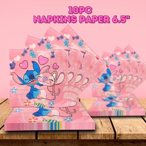 May include: Pink paper napkins featuring a cartoon character design. The napkins are decorated with hearts, musical notes, and images of the characters. The text "10PC NAPKINS PAPER 6.5"" is printed at the top. The napkins are stacked on a wooden surface.