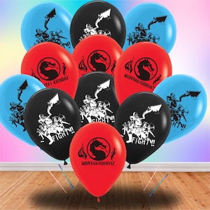May include: A collection of colorful balloons in blue, red, and black. Each balloon features a graphic design with the text "FIGHT!!" or "MORTAL KOMBAT". The balloons are arranged on a wooden surface.
