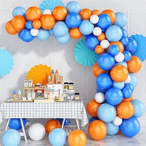 May include: A party scene featuring a balloon arch in orange, blue, and white. The arch surrounds a table laden with desserts, such as ice cream cones and a cake. Blue and orange paper fans decorate the scene, creating a celebratory atmosphere.