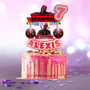 Puede incluir: Una tarta de cumplea&ntilde;os con glaseado rosa y un adorno para tarta con tem&aacute;tica de Deadpool. El adorno incluye el nombre "Alexis", el n&uacute;mero "7" y las palabras "Happy Birthday" y "Deadpool". La tarta est&aacute; decorada con chispas.