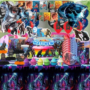May include: A colorful birthday party scene with Godzilla and King Kong themed decorations. Includes foil balloons, banners, cake, cupcakes, and figurines. The cake topper reads "Happy Birthday Matthew".