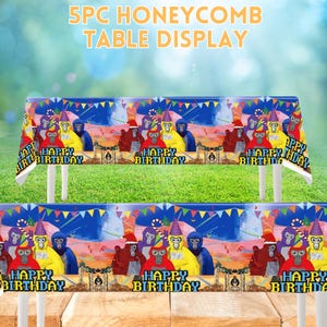 May include: A 5-piece honeycomb table display featuring a colorful birthday-themed design. The tablecloths display cartoon gorillas wearing party hats, with the text "HAPPY BIRTHDAY" repeated across the front. The background is a blurred green and blue.