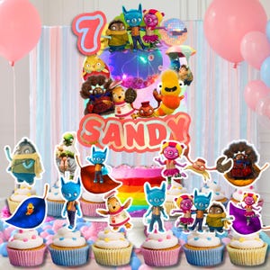May include: A birthday party scene with a cake and cupcakes decorated with cartoon character toppers. The cake has a rainbow design and the name "SANDY". Pink and blue balloons are in the background.