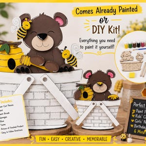 以下が含まれることがあります： クマとミツバチの巣の形をしたレーザーカット木製パーツ、絵の具、筆、スポンジ、接着剤、紐が入ったDIYクラフトキット。説明書と完成品の写真が含まれており、塗装済みキットまたは未塗装キットの選択肢が示されています。
