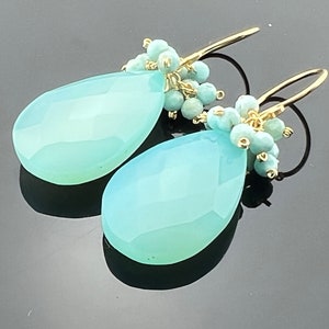 Peut inclure: Une paire de boucles d'oreilles turquoise en forme de larme avec un fil d'or et de petites perles turquoise.