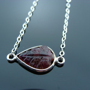 Puede incluir: Un collar de cadena de plata con un colgante en forma de l&aacute;grima con una piedra preciosa rosa tallada.