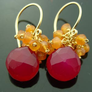 May include: Gold earrings with a cluster of orange carnelian beads and a large, faceted, pink chalcedony gemstone.