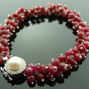 May include: A silver bracelet with a pearl clasp and red ruby beads.
