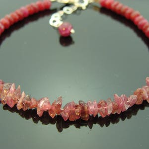 May include: A pink gemstone bracelet with a silver clasp. The bracelet is made of small, irregular shaped pink gemstones.