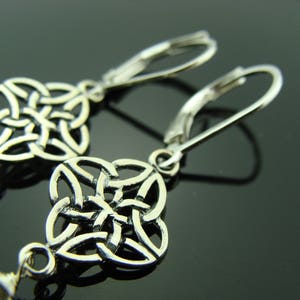 May include: Silver earrings with a Celtic knot design. The earrings are made of a silver metal and have a hook closure.