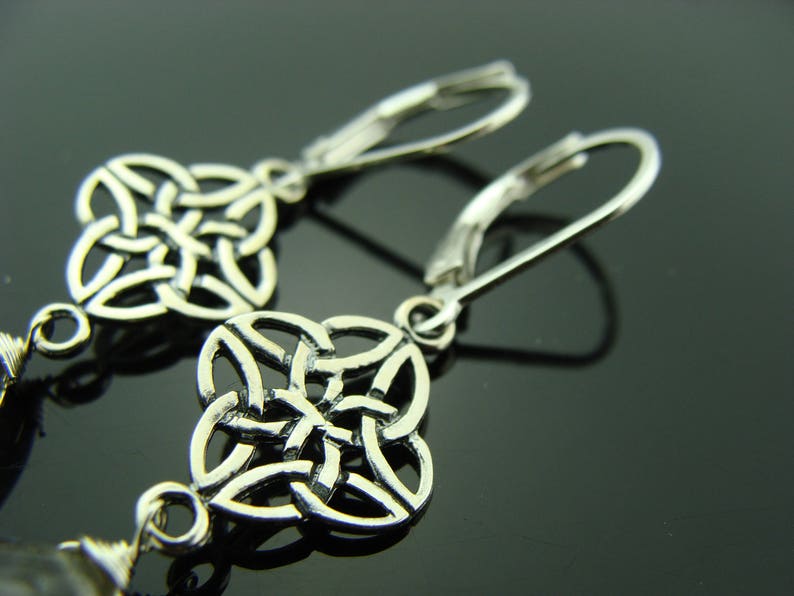 May include: Silver earrings with a Celtic knot design. The earrings are made of a silver metal and have a hook closure.
