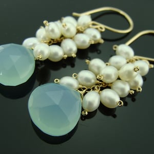 May include: Gold earrings with a teardrop-shaped light blue gemstone and a cluster of white pearls.