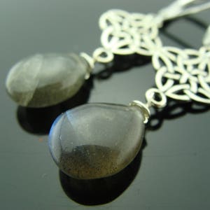 May include: Silver Celtic knot earrings with dark gray teardrop-shaped gemstone pendants.