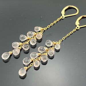 Pu&ograve; includere: Un paio di orecchini pendenti in oro con un design a cascata di pietre preziose rosa pallido a forma di lacrima.