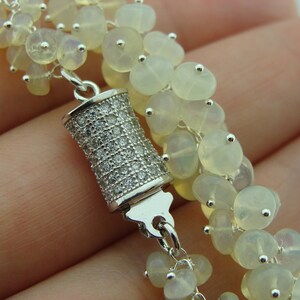 May include: A silver bracelet with a cluster of white opal beads and a silver clasp with clear cubic zirconia stones.