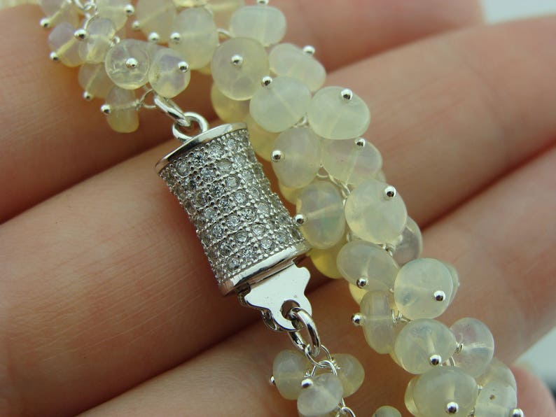 May include: A silver bracelet with a cluster of white opal beads and a silver clasp with clear cubic zirconia stones.