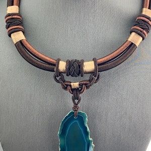 Pu&ograve; includere: Una collana di corda intrecciata marrone e beige con un ciondolo in agata verde. Il ciondolo &egrave; una pietra naturale con un motivo unico.