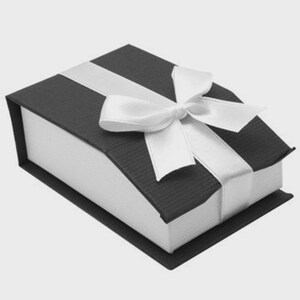 May include: A black gift box with a white satin ribbon and bow. The box has a textured surface and a contrasting white interior. The bow is centered on the top of the box.