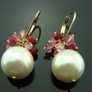 May include: Gold earrings with a large white pearl and pink gemstone accents.