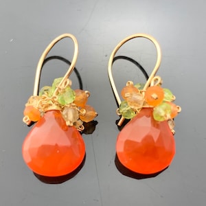 May include: Gold dangle earrings with a teardrop shaped carnelian gemstone and a cluster of smaller carnelian, peridot, and citrine gemstones.