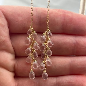 Pu&ograve; includere: Orecchini d'oro con un design a cascata di cristalli di quarzo trasparenti.