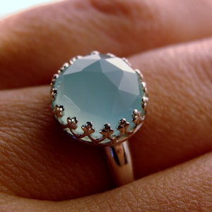 May include: A silver ring with a light blue gemstone set in a delicate floral design.