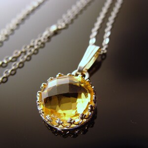 May include: A silver chain necklace with a yellow gemstone pendant. The pendant is set in a silver filigree frame.