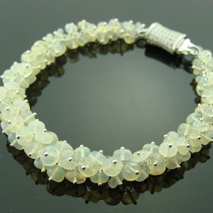 May include: A silver bracelet with a clasp closure, featuring a cluster of white opal beads.