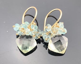 May include: Gold earrings with a large light green gemstone and smaller light blue gemstones.
