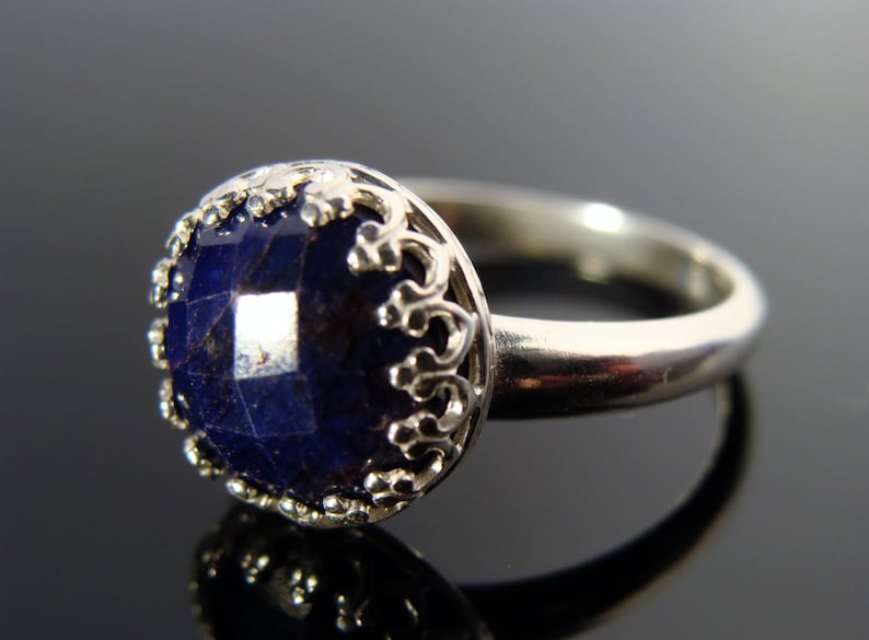 May include: A silver ring with a dark blue gemstone set in a filigree design.