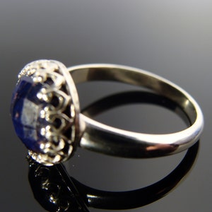 May include: A silver ring with a blue gemstone set in a filigree design.