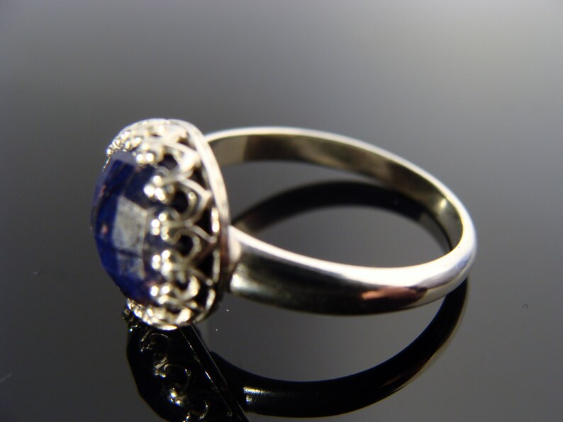 May include: A silver ring with a blue gemstone set in a filigree design.